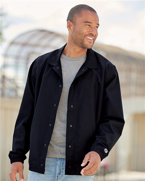 smiling male model wearing champion coachs jacket in black