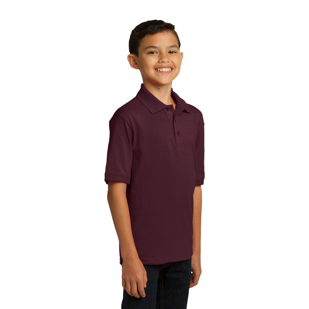 smiling child model wearing port & company youth knit polo in athletic maroon