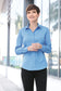 smiling model wearing port authority womens long sleeve poplin shirt in carolina blue